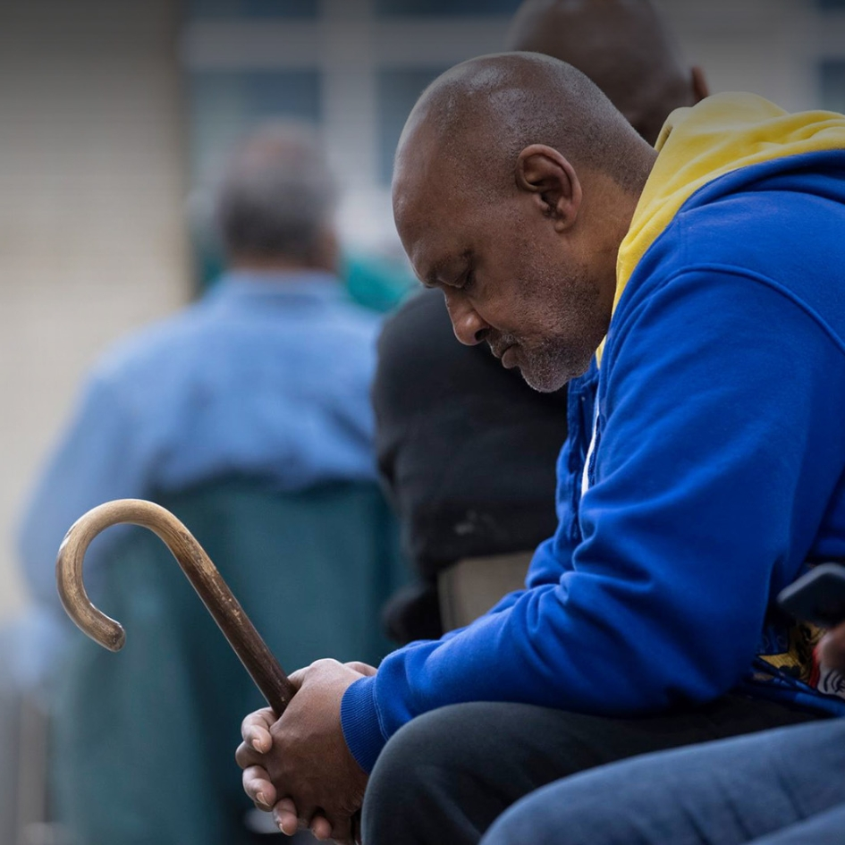 A man sitting down holding a cane