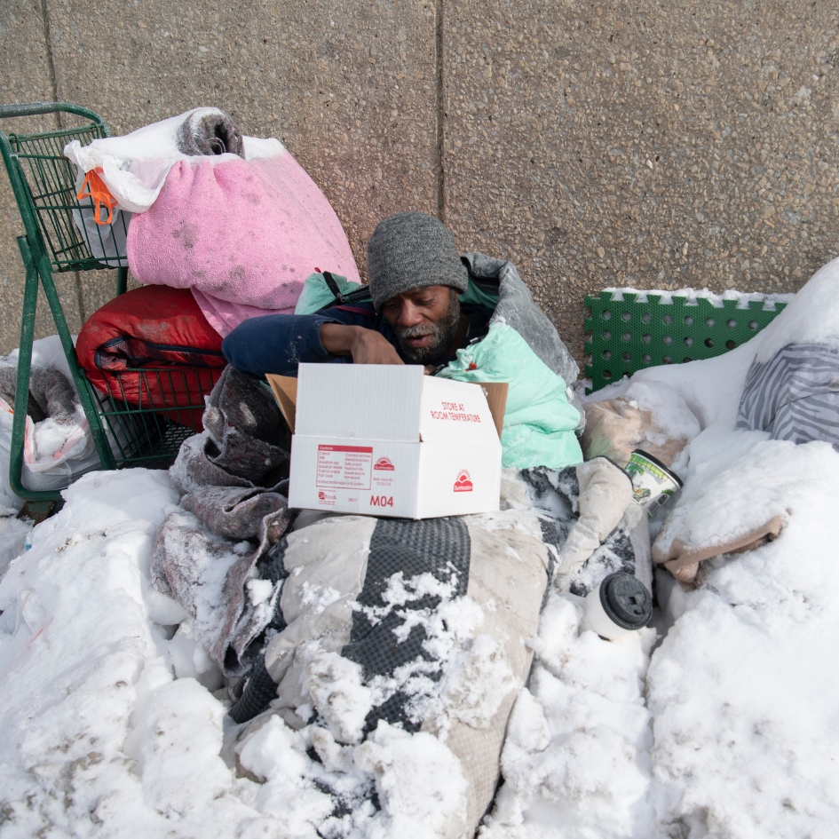 Homeless man in the snow receiving care package
